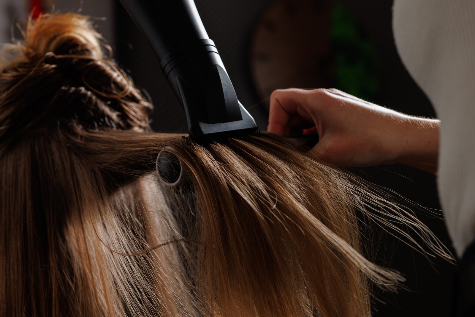 hairdresser drying hair with hair dryer and comb in beauty salon, drying hair close-up